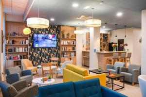 a waiting room with couches and chairs and a tv at Best Western Plus Le Havre Centre Gare in Le Havre