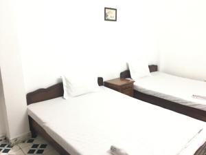 2 camas en una habitación con sábanas blancas en NHÀ NGHỈ THÀNH THU en Hanói