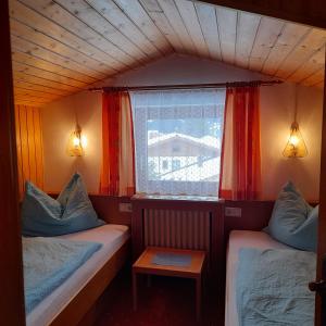 Habitación pequeña con 2 camas y ventana en Haus Gappmaier, en Filzmoos