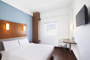 a bedroom with a bed and a table and a tv at Amaris Hotel Gorontalo in Gorontalo +14 photos
