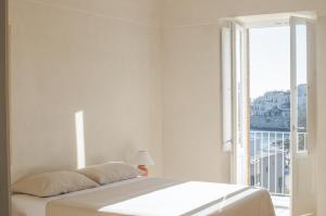 een witte slaapkamer met een bed en een groot raam bij Casa Pinta Rooms in Vieste