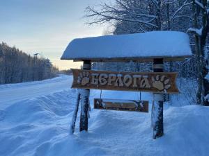 a snow covered sign sitting on a snow covered road at База отдыха Берлога in Lumivaara