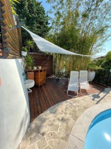 een houten terras met 2 stoelen en een zwembad bij Casa Milena elegante dimora con piscina privata in Albissola Marina