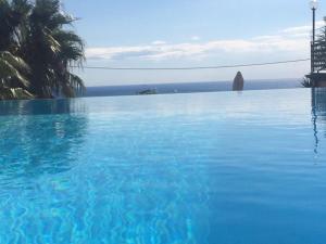 een groot blauw zwembad met uitzicht op de oceaan bij Casa Milena elegante dimora con piscina privata in Albissola Marina