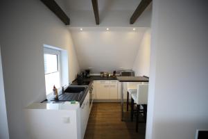 eine weiße Küche mit einer Spüle und einer Theke in der Unterkunft Eine sehr gemütliche Dachgeschoß Ferienwohnung in Ihlow