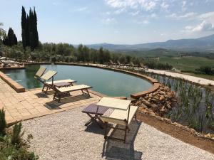 a swimming pool with picnic tables and a view of the mountains at A440 in Tuscany in Pienza