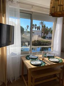 a dining room table with a view of a window at Vue sur l’eau in Cap d'Agde