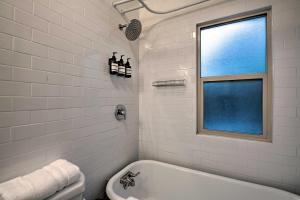 a white bathroom with a tub and a window at Modernized SLC Duplex with Yard about 4 Mi to Dtwn! in Salt Lake City +20 photos
