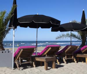un grupo de sillas y una sombrilla en la playa en Vittoria Immobilier 4 - Rez-de-jardin - Terrasse - chèques vacances acceptés, en La Grande-Motte
