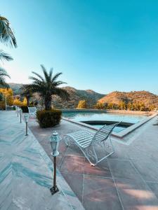 un banc à côté d'une piscine avec des montagnes en arrière-plan dans l'établissement The HighGarden Resort, à Udaipur