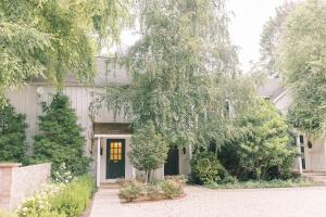 a white house with a black door and trees at Fairville Inn in Chadds Ford