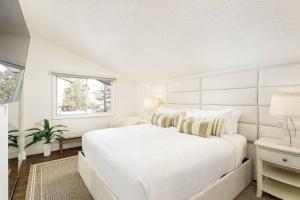 a white bedroom with a large bed and a window at 700 Monarch 301 in Aspen +39 photos