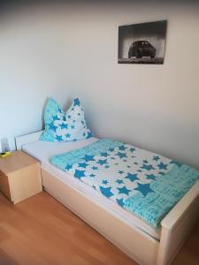 Cama pequeña con sábanas y almohadas azules y blancas en Wendler`s Haus en Meuselwitz