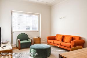 1 sofá naranja y 2 sillas en la sala de estar. en Akicity Amoreiras Sky, en Lisboa