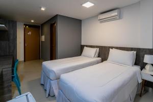 a hotel room with two beds and a table and a chair at Hotel Mais1 in Campina Grande