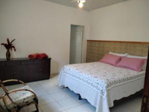Un dormitorio con una cama con almohadas rosas y una silla en Pousada Manga Rosa, en Chapada dos Guimarães