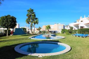 2 piscines dans une cour plantée de palmiers et de bâtiments dans l'établissement Aldeia Joinal - Swimming Pool - FREE WIFI - BY BEDZY, à Albufeira