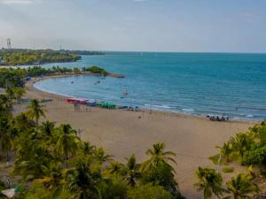 a beach with palm trees and people in the water at Cabañitas del Mar by Rotamundos in Coveñas