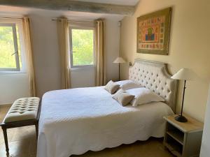 a bedroom with a large white bed with two windows at Villa des Roses in Roussillon