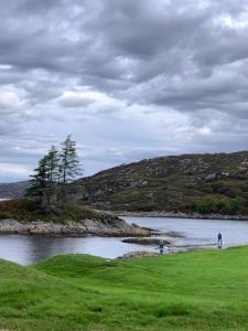 zwei Menschen, die am Ufer eines Wasserkörpers stehen in der Unterkunft Lochinver Holiday Lodges & Cottages in Lochinver