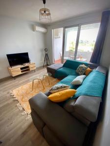 a living room with a blue couch with pillows at Le Bon'Appart in Saint-Gilles les Bains