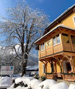 una casa de madera con un árbol en la nieve en Der Ulmenhof, en Gosau