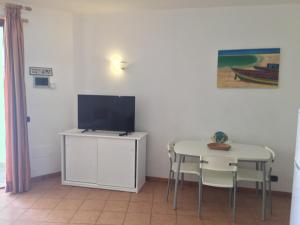 Il comprend un salon doté d'une télévision et d'une table avec des chaises. dans l'établissement Apt14 Porto Antigo 1 with Pool and Beach views, à Santa Maria