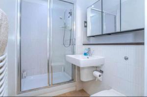 baño blanco con ducha y lavamanos en Oswald Apartment - Glasgow City Centre en Glasgow