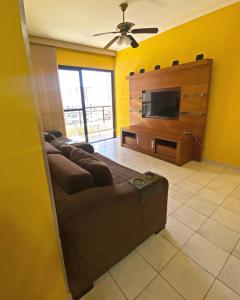 uma sala de estar com um sofá e uma televisão de ecrã plano em Apto 94 m2 mobiliado e decorado sacada panorâmica Condomínio Green Park no centro da Vila Caiçara - P Grande na Praia Grande