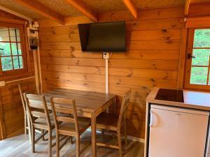 een eetkamer met een houten tafel en een tv aan de muur bij Leśne Zacisze in Poddąbie