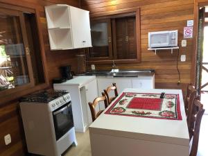 cocina con mesa, fogones y microondas en Chalés De Luxe Gramado, en Gramado