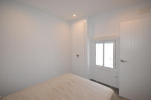 a white bedroom with a bed and a window at Apartamento La Ola in Conil de la Frontera