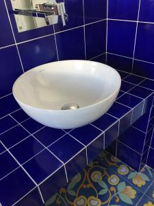 ein Badezimmer mit einem weißen Waschbecken an einer blau gefliesten Wand in der Unterkunft Casa Costiera in Porto Cesareo