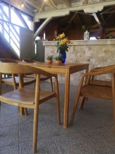 a wooden table and chairs with a vase of flowers on it at Makis Nest Family Apart-hotel Vourvourou in Vourvourou