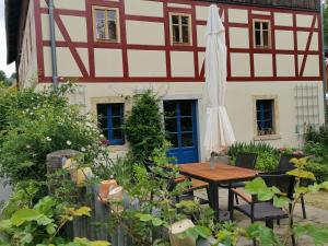 une table et un parasol devant une maison dans l'établissement Urlaub im 200 Jahre alten Fachwerkhaus, à Lichtenhain