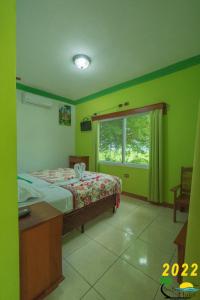 a bedroom with green walls and a bed and a window at Sun Breeze Hotel in El Remate
