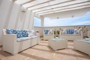 a living room with white wicker chairs and tables at Hotel Perla Dello Ionio in Torre Lapillo