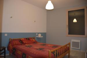 a bedroom with a bed with a red comforter and a window at Maison bord de mer avec jacuzzi in Névez