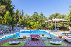 una mesa con copas de vino en una mesa cerca de una piscina en Villa Nefeli en Yenion