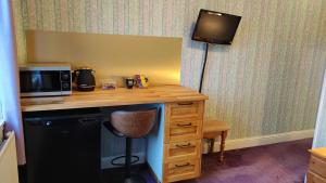 a room with a desk with a microwave and a television at Herrislea House Hotel in Tingwall