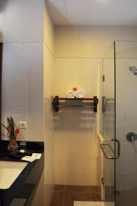 a bathroom with a glass shower and a sink at Tetirah Boutique Hotel Salatiga in Salatiga