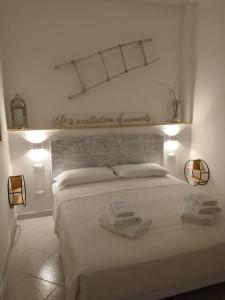 1 dormitorio blanco con 1 cama con 2 toallas en White House en Torre Canne