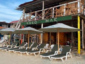 Un grupo de sillas y sombrillas frente a un edificio. en Raw KokoMar PosadaNativa, en Barú