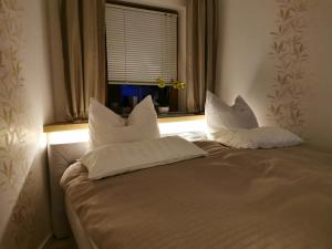 1 cama con almohadas blancas en una habitación con ventana en Ferienwohnung und Pension Gürtler, en Mohlsdorf