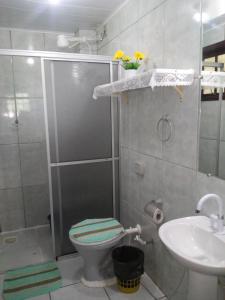 a bathroom with a shower and a toilet and a sink at Pousada Ilha Margarita in Florianópolis