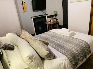 1 dormitorio con 1 cama con almohadas y TV en The Compasses Inn en Fordingbridge