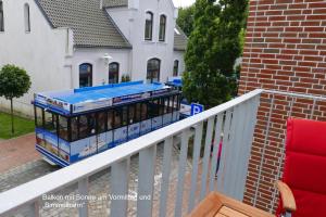 um autocarro turístico em frente a uma casa em Pole Poppenspäler mit Ladestation em Büsum