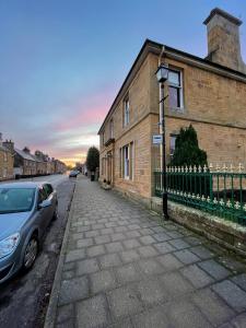 a car parked on a street next to a brick building at The Old Bank House Self Catering Apartment Dornoch in Dornoch