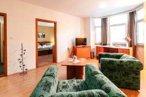 ein Wohnzimmer mit 2 grünen Stühlen und einem Tisch in der Unterkunft hotel ADRIA in Trenčianske Teplice