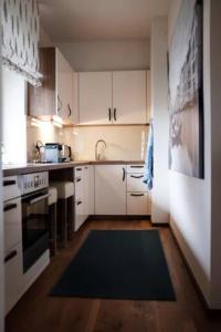 a kitchen with white cabinets and a black stove top oven at Großzügiges, stilvolles, charmantes Appartement in Salzburg by Fiorentino in Salzburg